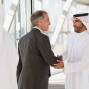 Businessman in suit shaking hands with businessman in kaffiyeh