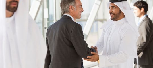 Businessman in suit shaking hands with businessman in kaffiyeh